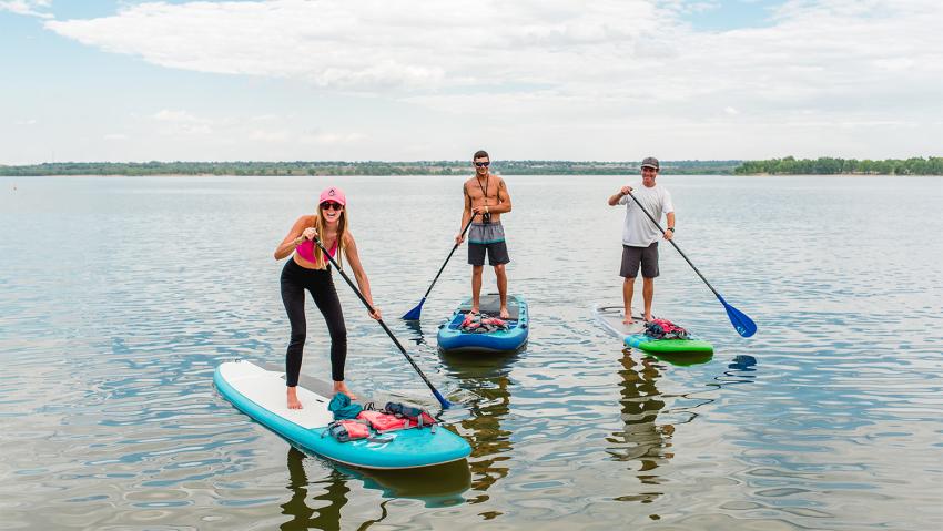 Three friends pose on their paddleboards at Cherry Creek State Park in Aurora Colorado