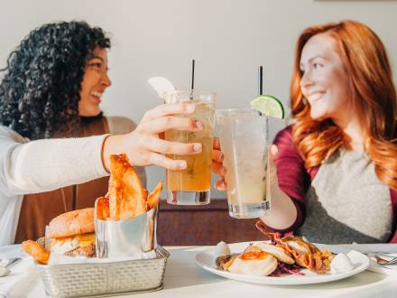 Two friends click glasses at Baba & Pops in Aurora Colorado