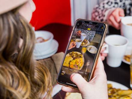 A young woman snaps a picture of her brunch at Three Little Griddles in Aurora CO