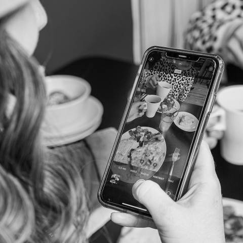 A young woman snaps a picture of her brunch at Three Little Griddles in Aurora CO