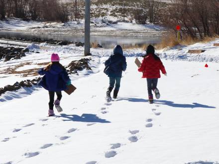 Three kids race in the snow during a nature adventure in Aurora, Colorado