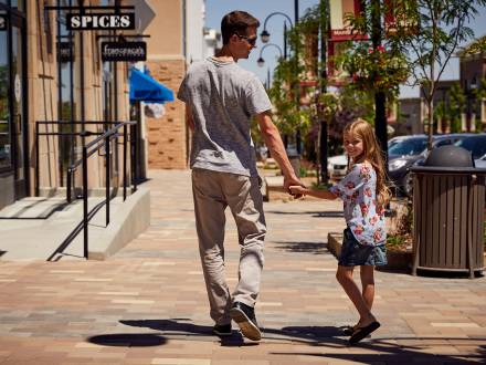 A father and a daughter walk hand-in-hand in Southlands in Aurora, Colorado