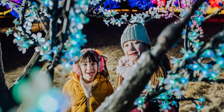 Two girls smile in the winter lights at Gaylord Rockies in Aurora CO