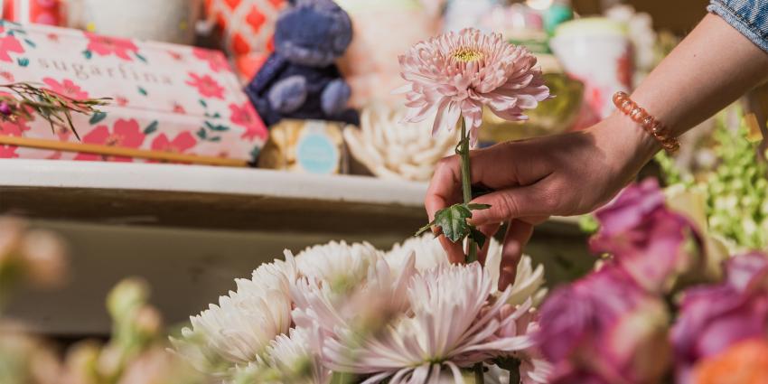 A young woman holds a flower at Poppy & Pine in Aurora Colorado