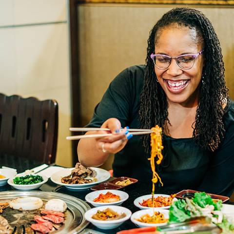 Young woman eats noodle dish at a Korean restaurant in  Aurora, Colorado