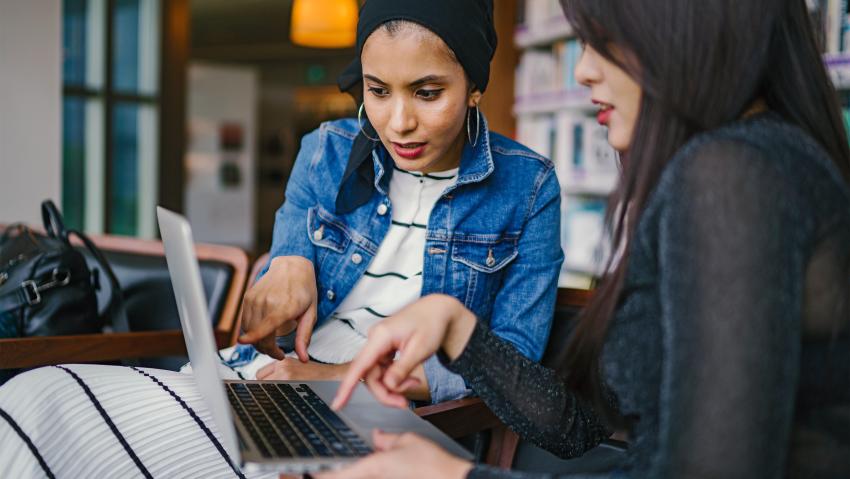 Two women looking at a laptop and applying for Aurora Small Business Loans