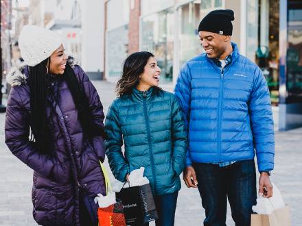 Three friends carry shopping bags through Southlands Shopping Center in Aurora CO