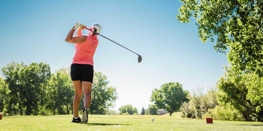 A woman takes a swing in Golf in Aurora colorado