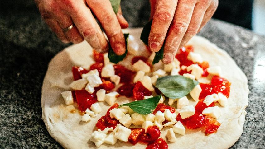 Man shapes and molds pizza before baking.